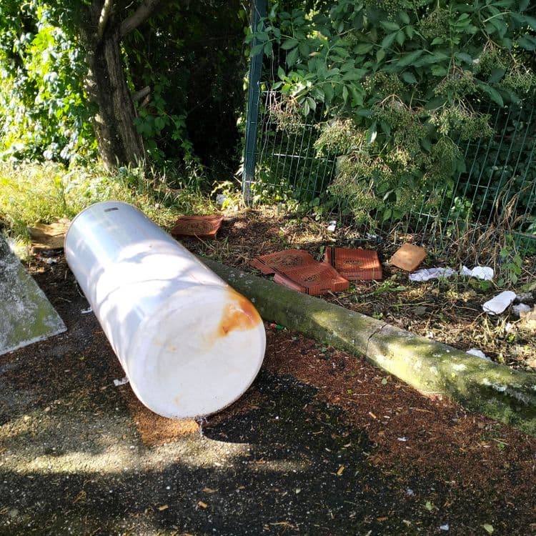 Chauffe eau abandonné et déchets divers au fond d'un parking public 