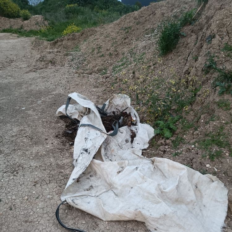 Petit dépôt sauvage dans un vieux "big bag" de sable déchiré avec détritus de toute sorte, canettes alu et verre, morceaux de ferraille, d'aluminium ...etc le tout mélangé à de la terre ou des déchets verts pourris.