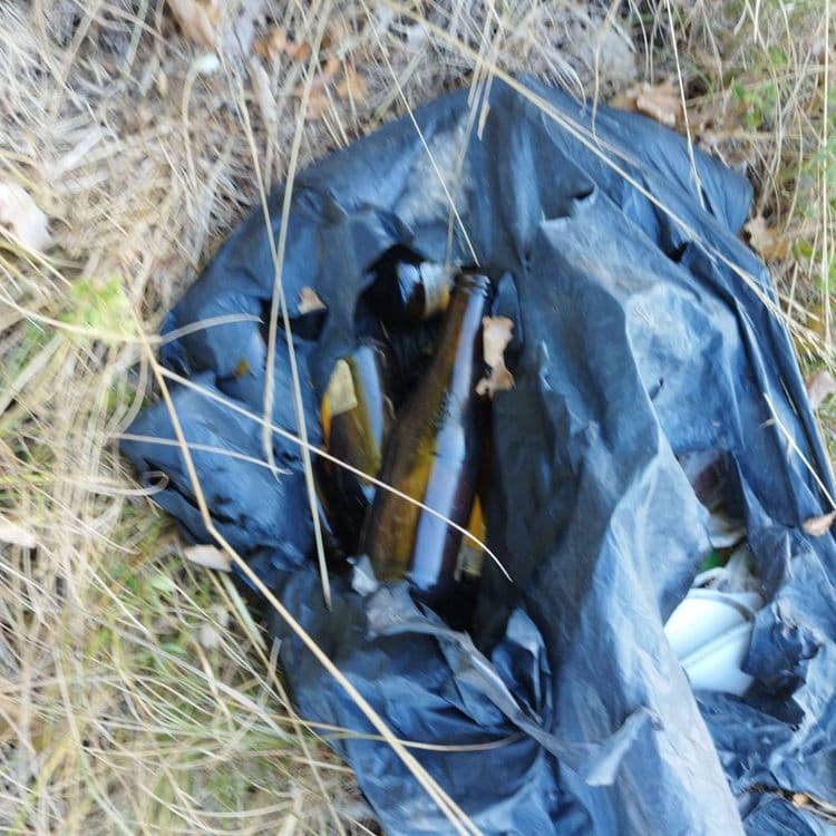 Dépôt d'un sac poubelle avec des bouteilles de bière et déchets plastiques 