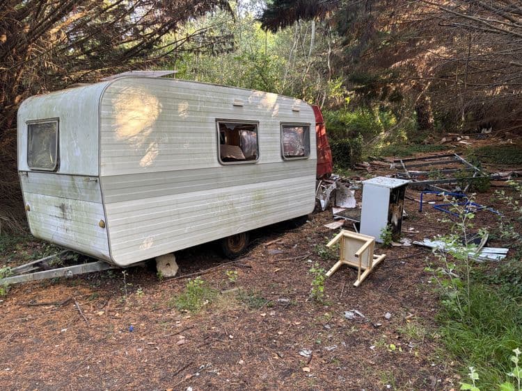 Voici une estimation des déchets présents sur le site :

*   **Caravane abandonnée :** On peut estimer le poids de la caravane entre 700 kg et 1000 kg. Il s'agit d'un élément unique.

*   **Mobilier divers (table, chaise) :** Le poids total de ces éléments pourrait être estimé entre 10 kg et 20 kg. On observe au moins 1 table et 1 chaise.

*   **Électroménager (frigo?) :** Le poids de cet appareil pourrait être estimé entre 30 kg et 50 kg. Il s'agit d'un élément unique.

*   **Débris et éléments de construction/démolition :** Il est difficile d'estimer précisément le poids de ces débris sans une inspection plus approfondie, mais on peut raisonnablement estimer entre 50 kg et 100 kg. La quantité est importante, avec divers morceaux éparpillés.
