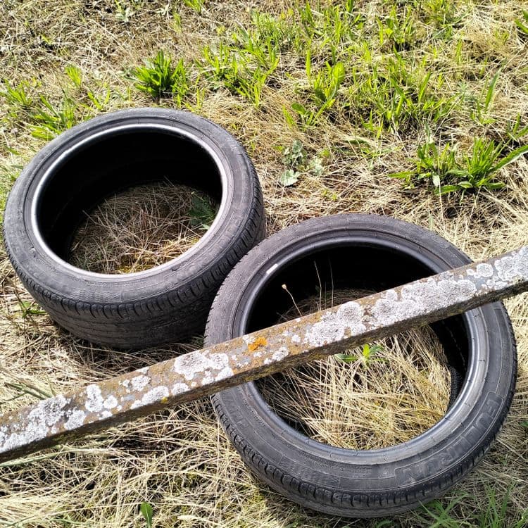 Deux pneus usagés au bord de la route en zone industrielle 