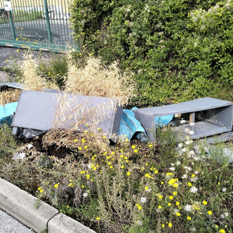 Jardinières en bois jetées à côté d'un portail d'accès en zone industrielle 