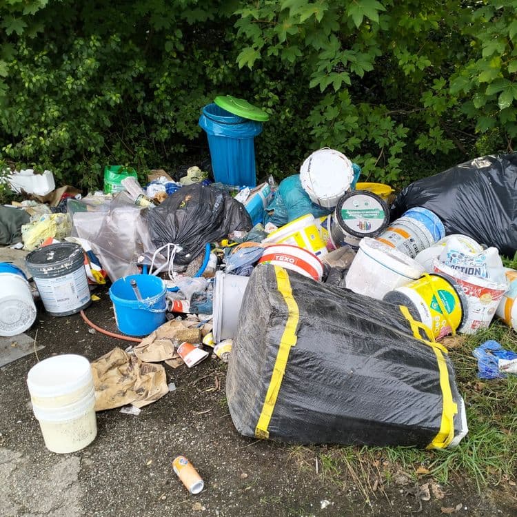 Pots de peinture et déchets divers abandonnés sur un parking public 