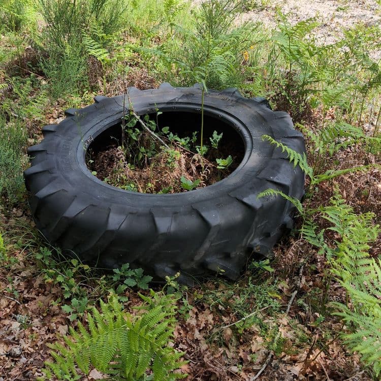 Pneu de tracteur en bordure d'une piste et à environ 100 m d'une route goudronnée.