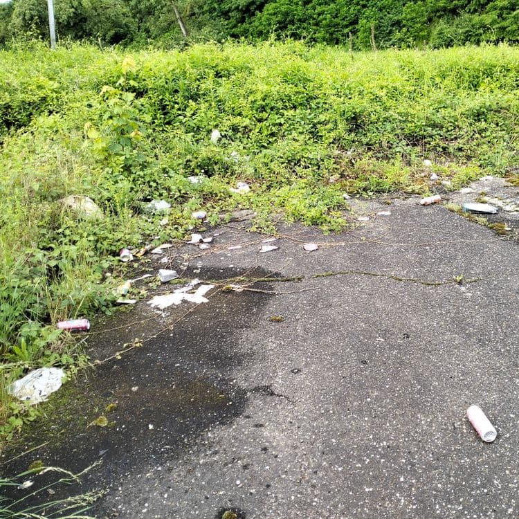 Détritus et déchets divers sur parking de zone industrielle et sur une voie ferrée à proximité 