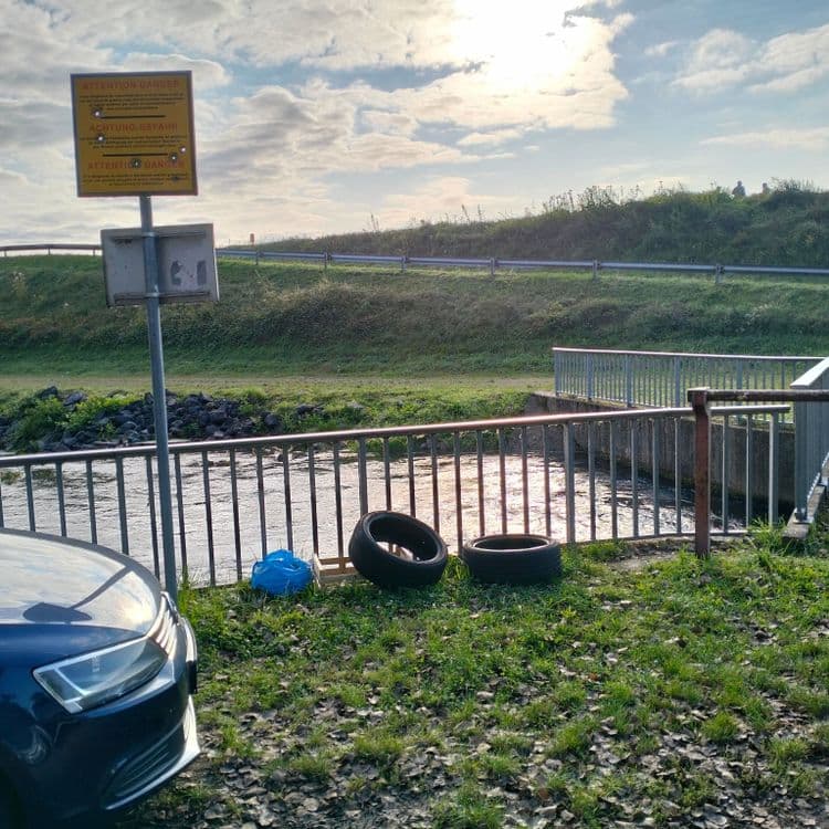 Pneus usagés et déchets divers au bord d'un ruisseau 
