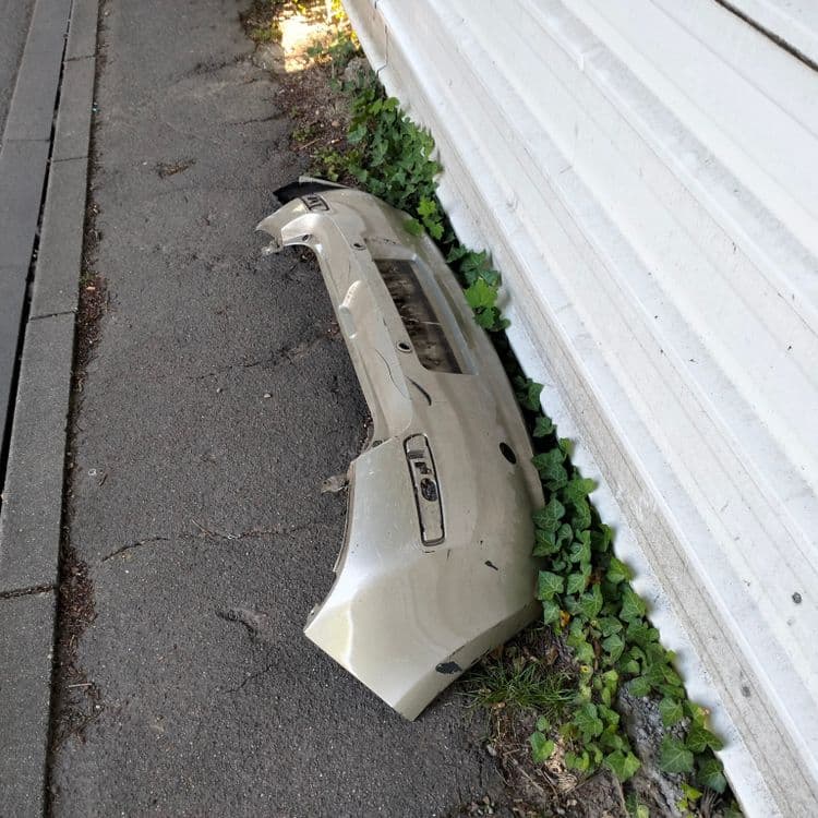 Pare choc de voiture abandonné sur un trottoir 