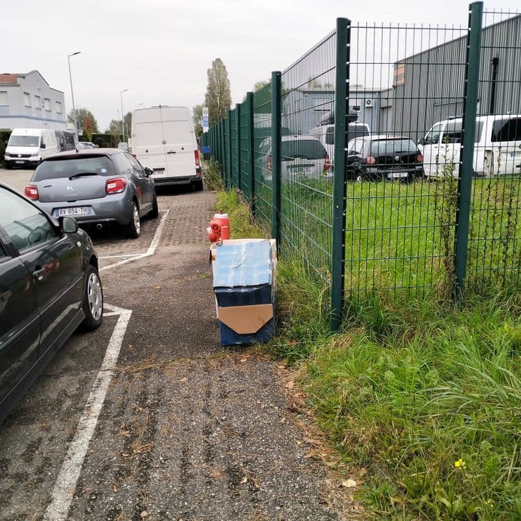 Cartons et déchets divers sur le trottoir en zone industrielle 