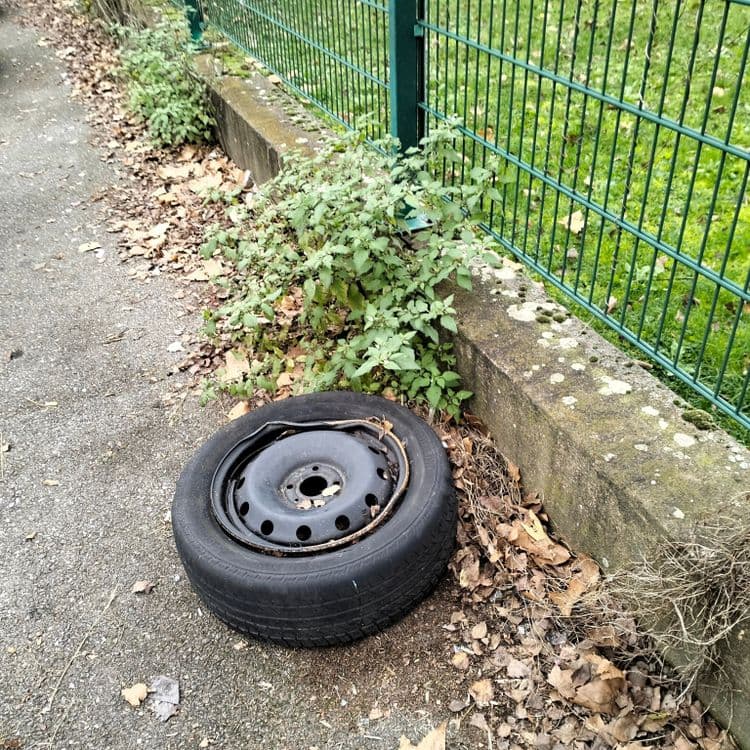 Roue complète abandonnée sur un parking privé 