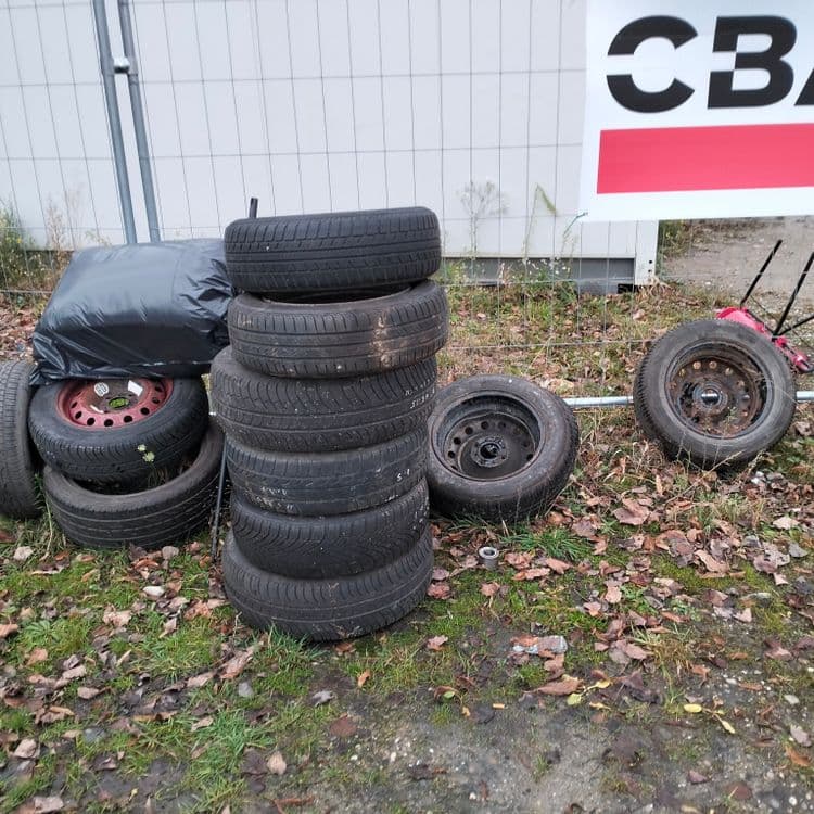 16 roues et un grand sac poubelle abandonnés à côté de baraques de chantier sur un terrain vague 