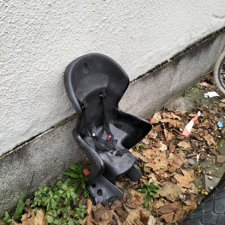 Siège enfant pour vélo abandonné à côté d'arceaux de stationnement 