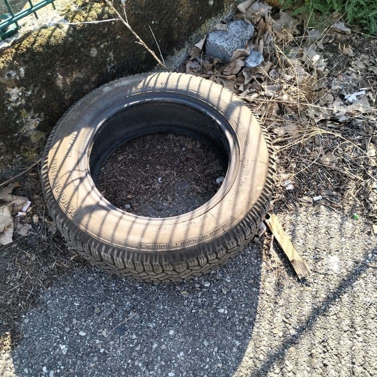 Pneus usagés abandonnés sur un parking public 