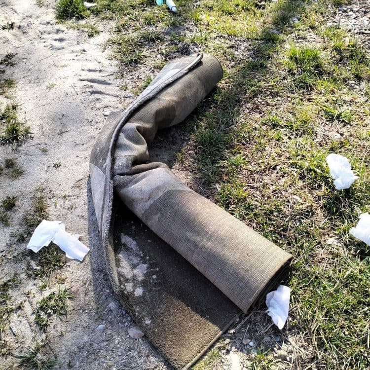 Un tapis et détritus divers abandonnés à proximité d'une voie ferrée 