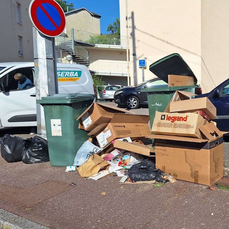 De  nombreux déchets sont déposés directement au sol (cartons, papiers, sacs poubelles...), ce qui crée un dépôt sauvage sur le trottoir.