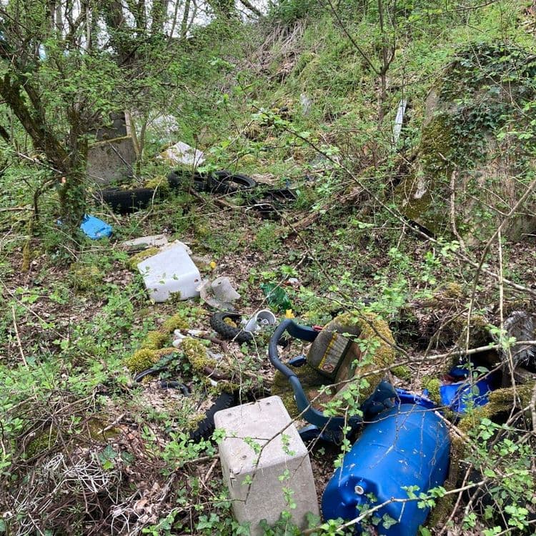 Voici l'analyse des déchets présents sur la photo :

On observe un dépôt sauvage comprenant divers types de déchets. On identifie des éléments suivants :

*   **Pneumatiques** : Environ 4 pneus, principalement des pneus de voiture et de moto. On estime le poids total à environ 40 kg.
*   **Plastiques divers** : Une grande variété de plastiques, incluant des bidons bleus (environ 2, pesant environ 10 kg chacun), des récipients blancs (environ 2, pour un total d'environ 5 kg), ainsi que des fragments et autres objets en plastique (estimés à 5 kg). Le poids total de ces plastiques divers est estimé à environ 35 kg.
*   **Déchets divers** : Des éléments de béton (environ 2 blocs, pesant environ 10 kg chacun), un siège enfant (estimé à 3kg), et d'autres déchets non identifiables précisément (environ 7 kg). Le poids total de ces déchets divers est estimé à environ 30 kg.

En résumé, le poids total des déchets présents sur la photo est estimé à environ 105 kg. 