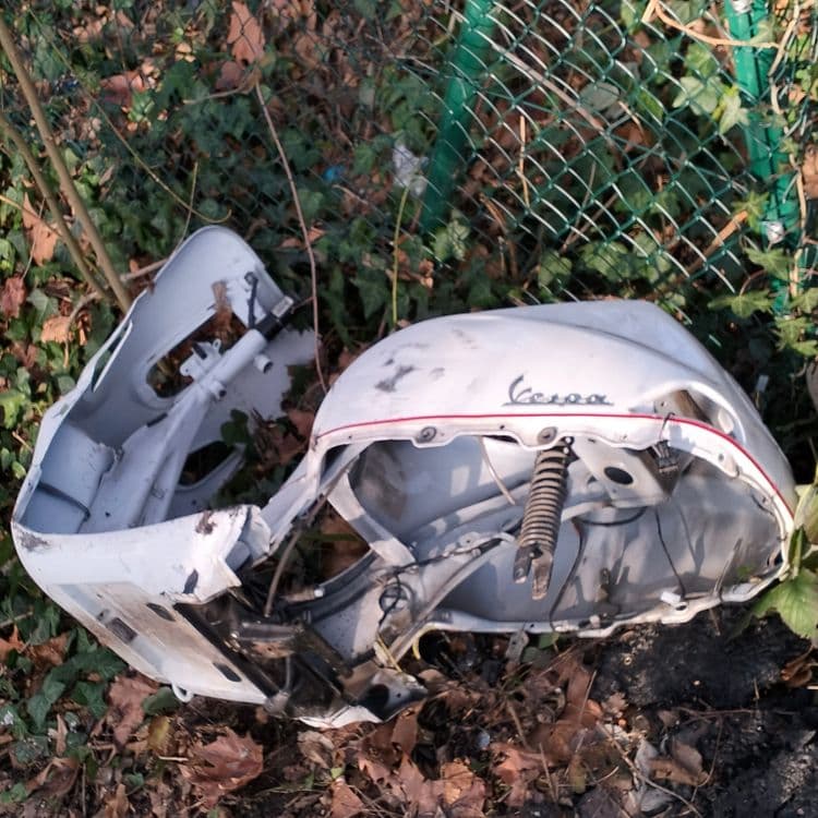 Carcasse de scooter Vespa abandonnée en lisière de forêt 