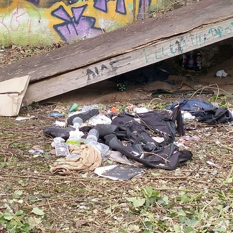 Vêtements et déchets divers abandonnés sur un terrain vague 