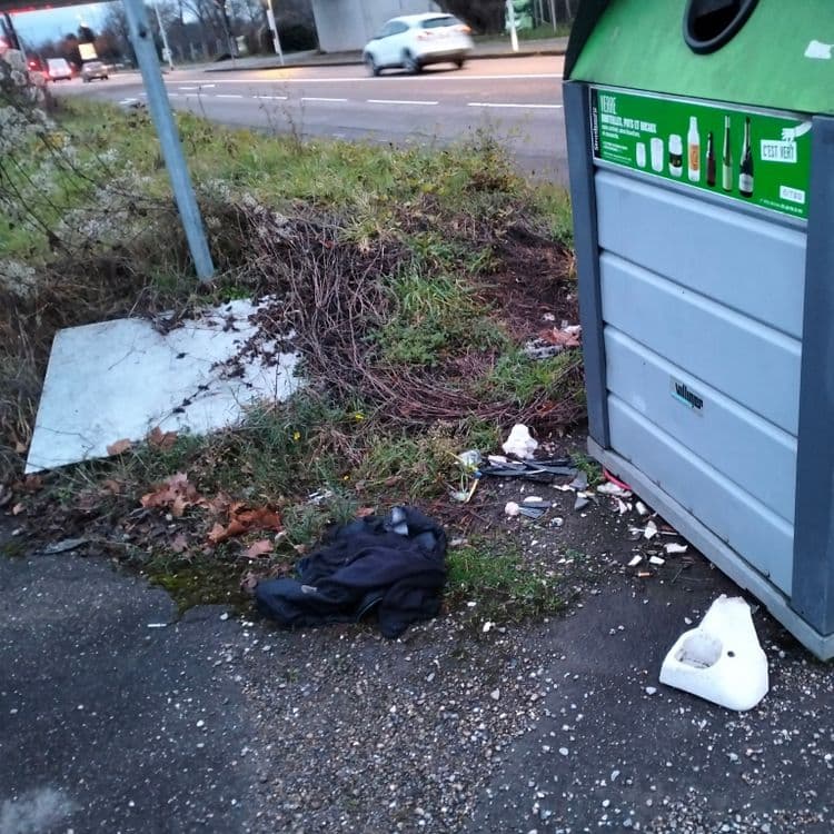 Pneu usagé et déchets divers à l'entrée d'un parking privé 