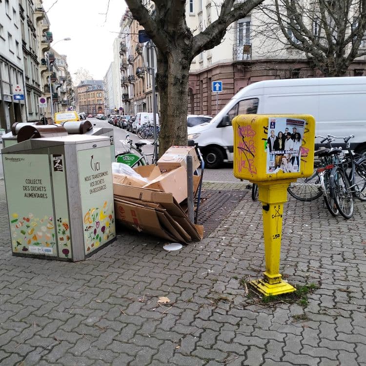 Grands cartons d'emballage abandonnés sur le trottoir à côté de container bio déchets 
