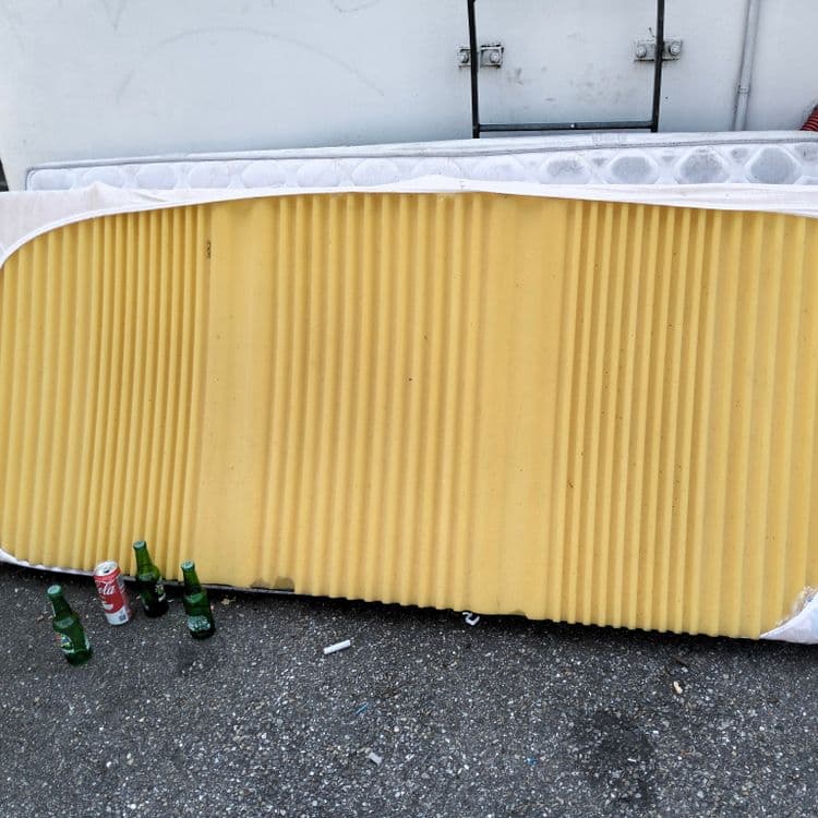 Matelas, sommier, mobilier divers à côté d'un container à vêtements 
