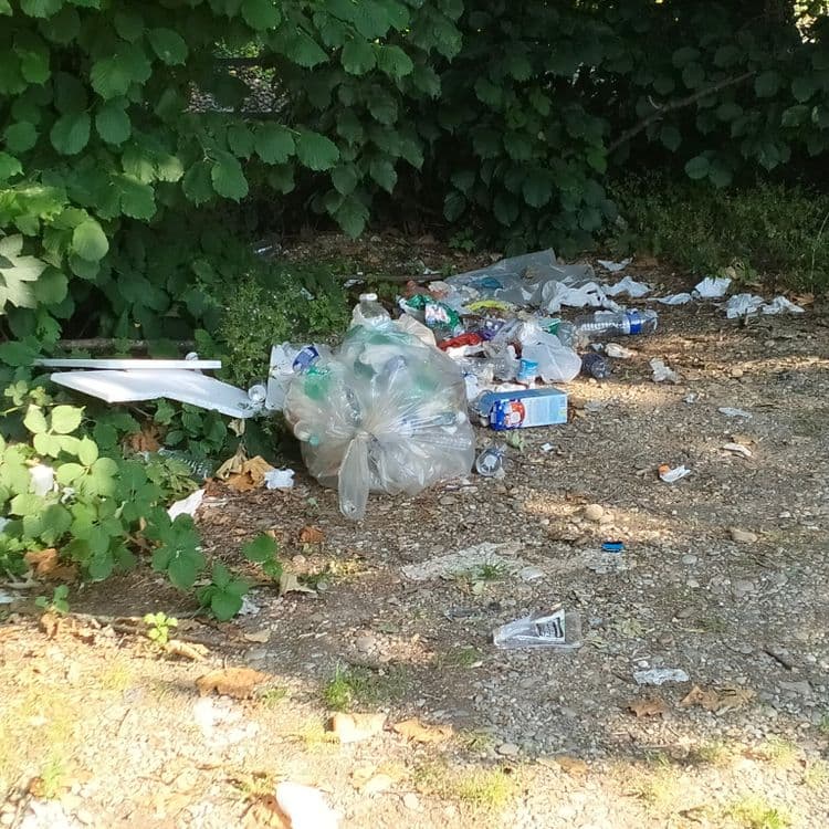 Sacs poubelles, gaines électriques et déchets divers abandonnés sur un chemin 