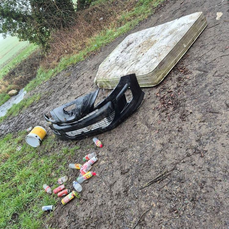 Les déchets présents sur l'image comprennent :

*   Un matelas usagé : Estimation du poids : 20 kg. Quantité : 1.
*   Un pare-chocs automobile en plastique noir : Estimation du poids : 5 kg. Quantité : 1.
*   Des bouteilles en plastique vides (principalement de boissons) : Estimation du poids total : 1 kg. Quantité : Environ 10.
*   Un pot de peinture vide : Estimation du poids : 0.5 kg. Quantité : 1.