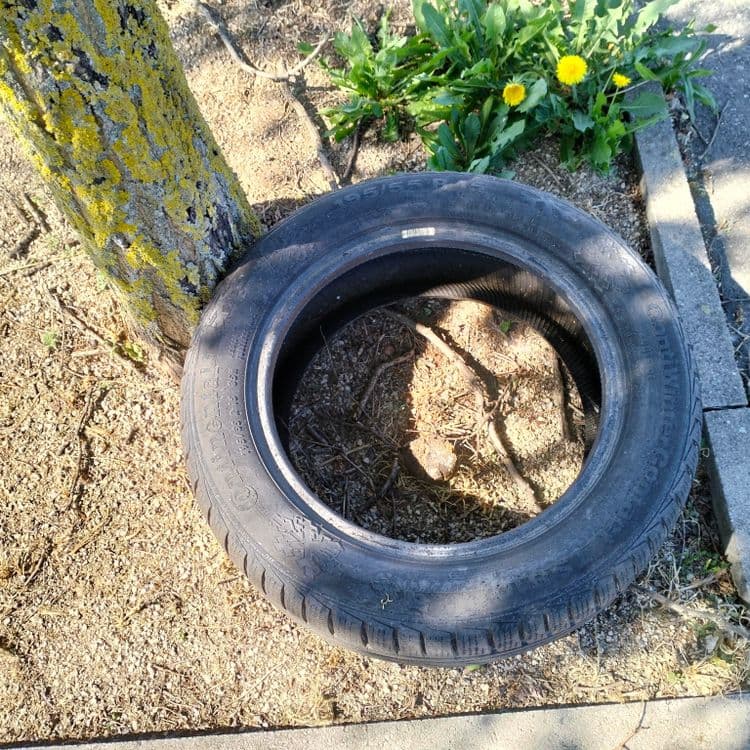 Un pneu usagé abandonné sur un parking de supermarché 