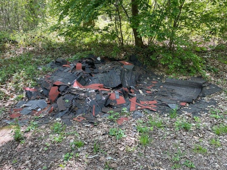 Analyse des déchets présents sur l'image :

L'image révèle un dépôt sauvage constitué principalement de déchets de toiture. On y observe une quantité importante de bardeaux bitumés, estimés à environ 200 unités. Ces bardeaux présentent une combinaison de couleurs noire et rouge. Le poids total de ces déchets de toiture est estimé entre 300 et 400 kilogrammes.
Le dépôt se trouve en forêt de Senart à l entrée après la route 