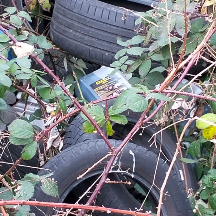 Pneus usagés et déchets divers abandonnés à côté d'un talus 