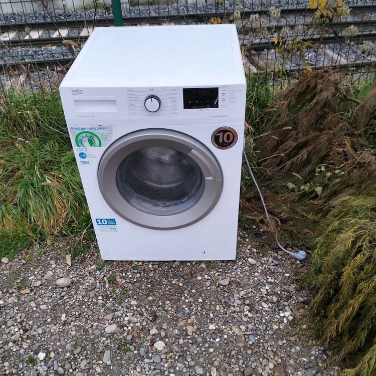 Déchets verts et une machine à laver abandonnés au bord de la route 