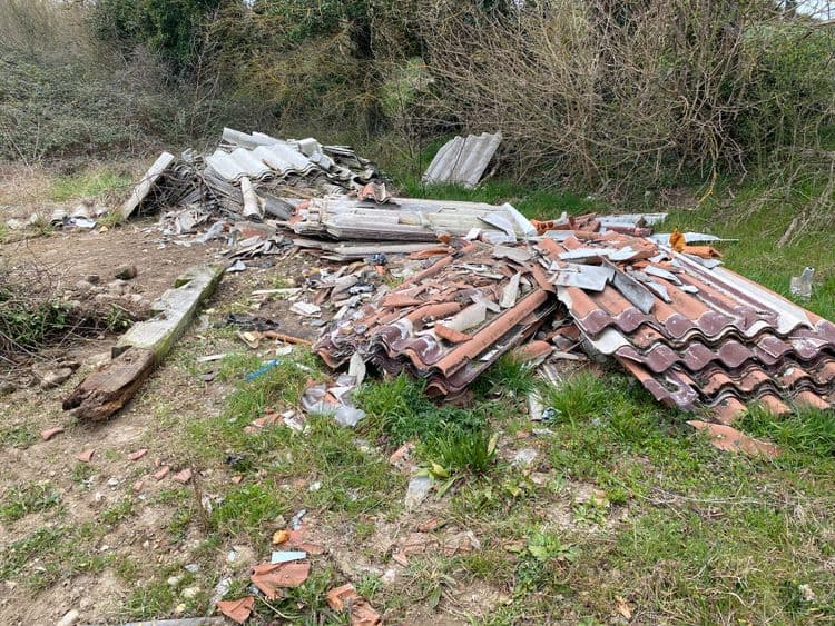Déchets constatés sur la photo :

- **Tuiles :** Il y a une importante quantité de tuiles en terre cuite cassées et entières.  L’estimation du poids est d’environ 200 kg,  soit environ 100 tuiles de taille moyenne.

- **Ardoises ou plaques ondulées en fibrociment :**  On observe un amas important de plaques ondulées, certaines cassées, d'autres entières.  Le poids est estimé à 150 kg, correspondant à environ 50 plaques de taille standard.

- **Bois :** Un morceau de bois de charpente, apparemment ancien et détérioré, est visible.  Le poids est difficile à estimer avec précision sur la base de l'image, mais on peut supposer environ 50 kg.

- **Déchets divers :**  Il y a des débris plus petits et non identifiables avec précision (morceaux de plastique, de métal, etc.).  Le poids total de ces déchets est estimé à 10 kg.

Total estimé : 410 kg de déchets.  Cette estimation est approximative et peut varier selon la taille et l'épaisseur exactes des matériaux.
