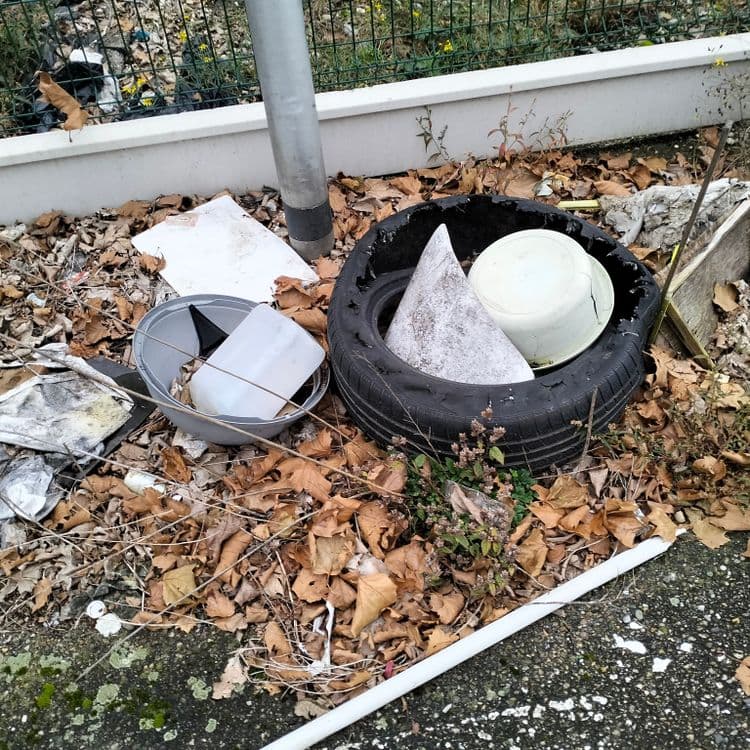 Pneu, déchets divers sur un trottoir dans une zone commerciale 