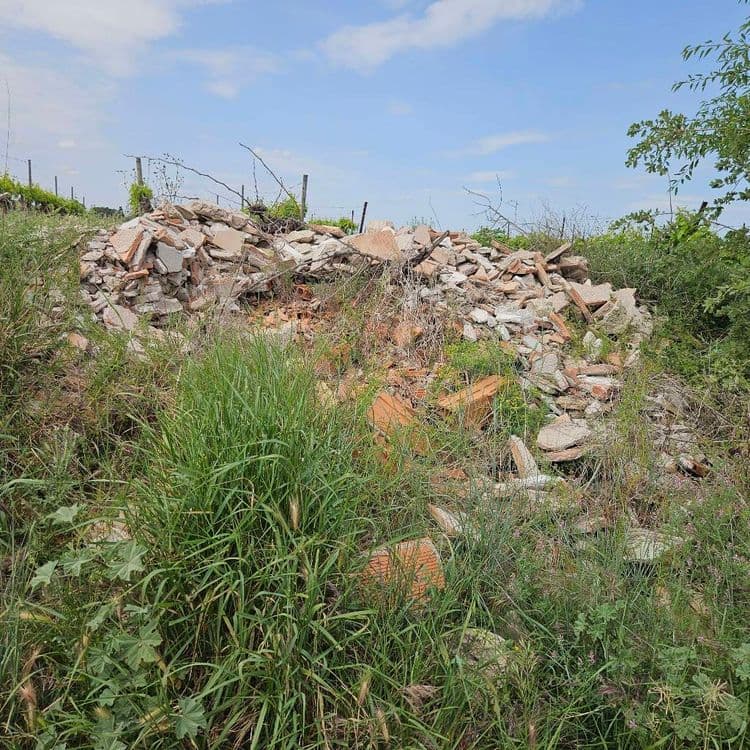 Voici une estimation des déchets présents sur le site :

*   **Débris de construction et de démolition (DCD) :** Il s'agit principalement de fragments de briques, de tuiles, de béton et potentiellement de plâtre. La quantité totale est estimée à environ 500 kg.
*   **Végétation sauvage :** Des herbes hautes, des broussailles et des branches sont présentes, envahissant la zone et mélangeant aux déchets de construction. Le poids de la végétation est estimé à 50 kg.