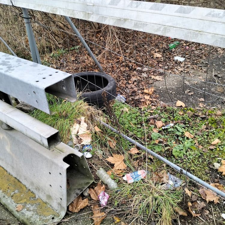 Pneus usagés et déchets divers abandonnés sur un chemin condamné 