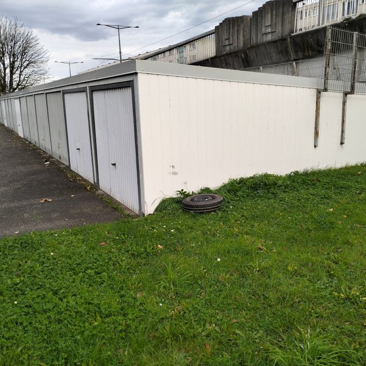 Une roue complète abandonnée à côté de garages privés 