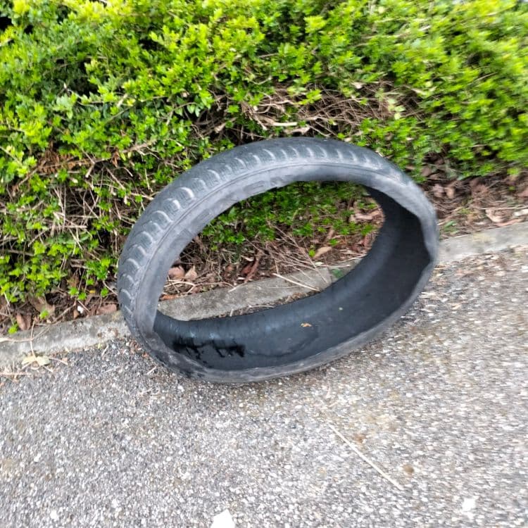 Un pneu usagé abandonné sur le trottoir 