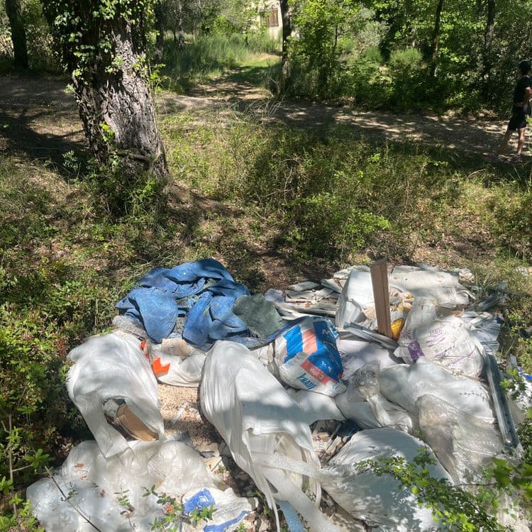 Analyse des déchets présents sur la photo :

*   **Sacs en plastique** : Nombreux sacs de différentes tailles, principalement blancs et transparents. Contenu indéterminé (probablement des gravats, des restes de matériaux de construction, etc.). Estimation du poids total : 20 kg, quantité estimée : 10 sacs.
*   **Gravats et déchets de construction** : Présence de morceaux de plâtre, de tuiles, de béton, de métal (profilés). Estimation du poids total : 40 kg.
*   **Bâche en plastique bleue** : Une bâche en plastique déchirée. Estimation du poids : 1 kg, quantité : 1.
*   **Sacs de matériaux** : Un sac de mortier "KNAUF Mak 3". Estimation du poids : 25 kg, quantité : 1 sac. Un sac de mortier "STD". Estimation du poids : 25 kg, quantité : 1 sac.
*   **Divers** : Divers petits déchets non identifiables (morceaux de bois, plastique...). Estimation du poids total : 3 kg.