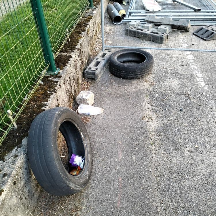Pneus usagés abandonnés sur un parking public 