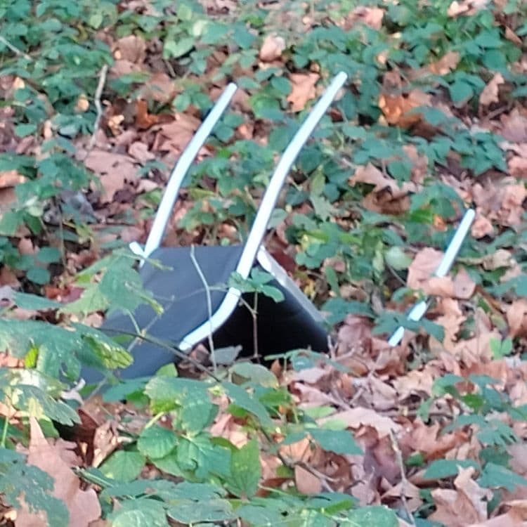 Un congélateur bahut, une chaise et divers déchets au bord de la route et de la voie ferrée 