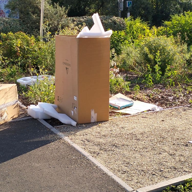 Carton et polystyrène abandonnés au bord d'une piste cyclable 