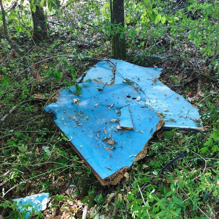 Les déchets abandonnés sont les suivants :

*   Des panneaux de bois aggloméré ou composite, de couleur bleue.
*   Des plaques de fibrociment