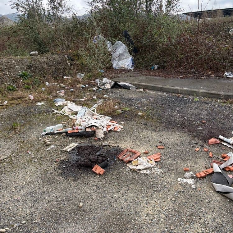 Voici une estimation des déchets présents sur le site :

Divers détritus (plastiques, papiers, emballages) : Une quantité significative de déchets divers est éparpillée sur la zone, avec un poids estimé à environ 5 kg.

Déchets de construction (tuiles, morceaux de bitume) : Les déchets de construction sont constitués principalement de tuiles cassées et de morceaux de bitume. On dénombre environ 150 tuiles entières ou fragmentées et plusieurs morceaux de bitume (environ 2 m²). Le poids total de ces débris est estimé à environ 50 kg.

Sacs poubelles éventrés : Un sac poubelle éventré et des déchets éparpillés sont visibles, laissant présager un volume initial de déchets contenu dans le sac d'environ 50 litres. Le poids est difficile à évaluer précisément, mais il pourrait atteindre 10 kg.

Divers textiles (chiffons, morceaux de tissu) : Une certaine quantité de textiles usagés est également présente, estimée à environ 3 kg.

Autres déchets : On observe également d'autres déchets divers tels que des bouteilles en plastique, des canettes et des objets non identifiables, représentant un poids estimé à environ 2 kg.
