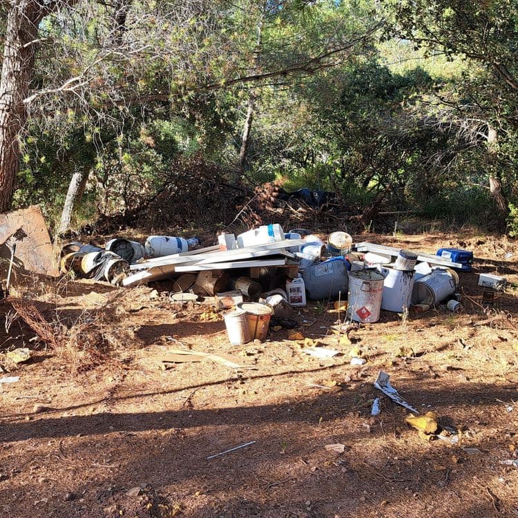 Suite à l'analyse de la photo, voici une estimation des déchets présents :

*   **Peinture et solvants (pots, bidons)** : Estimation de 25 kg, environ 15 contenants de différentes tailles.
*   **Débris de construction (bois, plâtre, métal)** : Estimation de 50 kg, divers éléments mélangés.
*   **Matériaux divers (plastique, textile)** : Estimation de 10 kg, comprend une bâche noire et des objets non identifiés.
*   **Feraille (barils)** : Estimation de 100 kg, environ 5 barils.