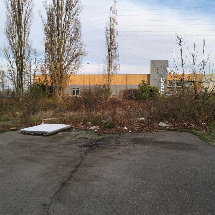 Un vieux matelas et déchets divers au fond d'une impasse en zone commerciale 