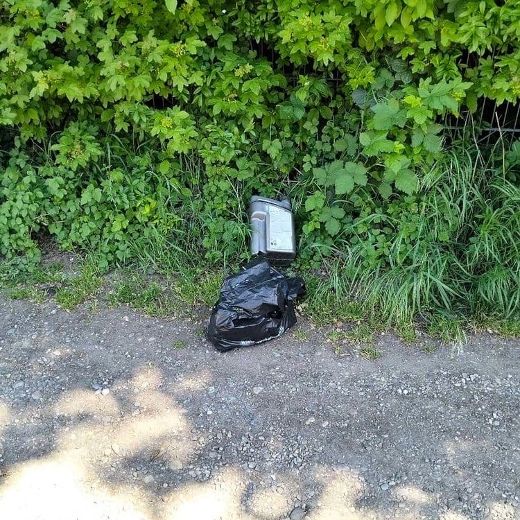 Bidon d'huile vide et sac plastique abandonnés au bord d'une route à l'arrière d'un hyper marché 