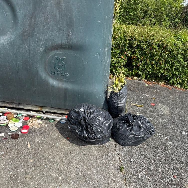 Sacs au sol à côté des apports volontaires verre et papier 