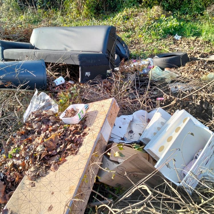 Mobilier, déchets divers, pneus usagés au bord d'un chemin donnant accès à un parc, à côté d'un cimetière 