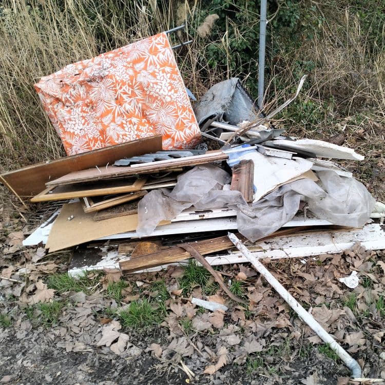 Pneus usagés en grande quantité et déchets divers abandonnés au bord d'une route forestière 