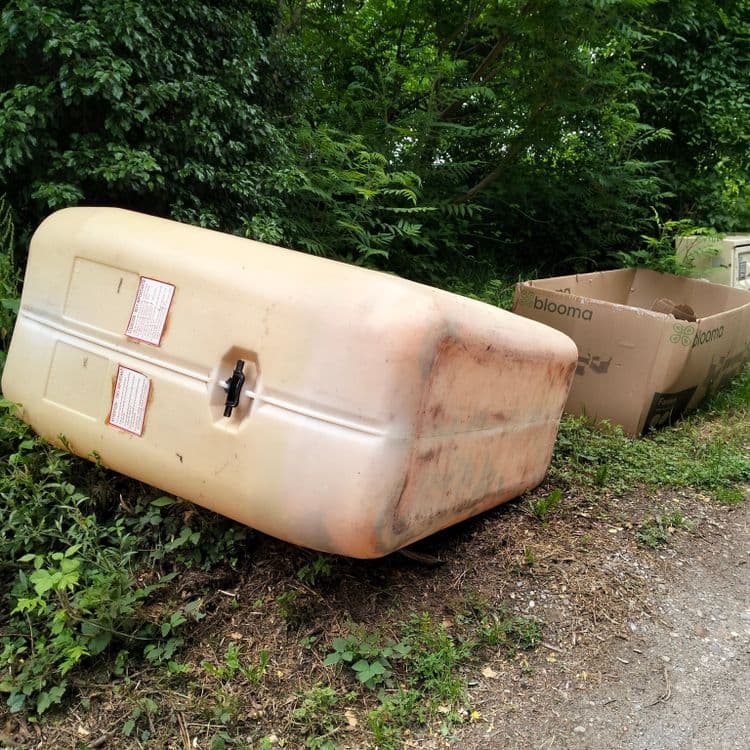 Cuve à mazout en plastique et carton vide au bord de la route 
