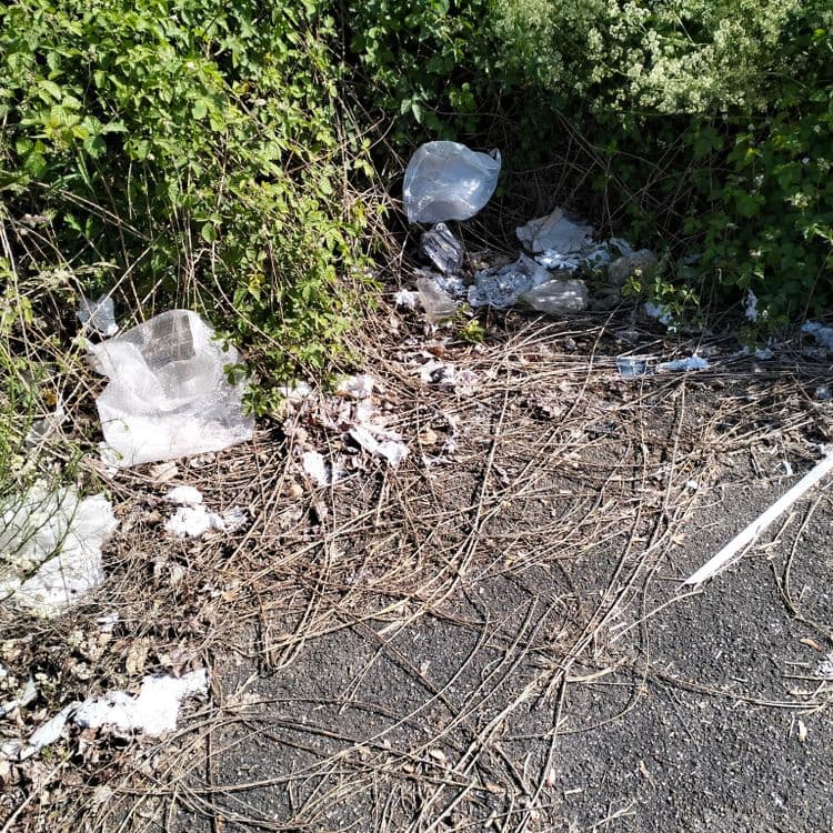 Déchets divers abandonnés sur un parking de zone commerciale 